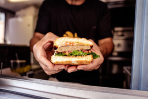 Person holding a cut-in-half burger showing the texture of a Bahama Burger patty