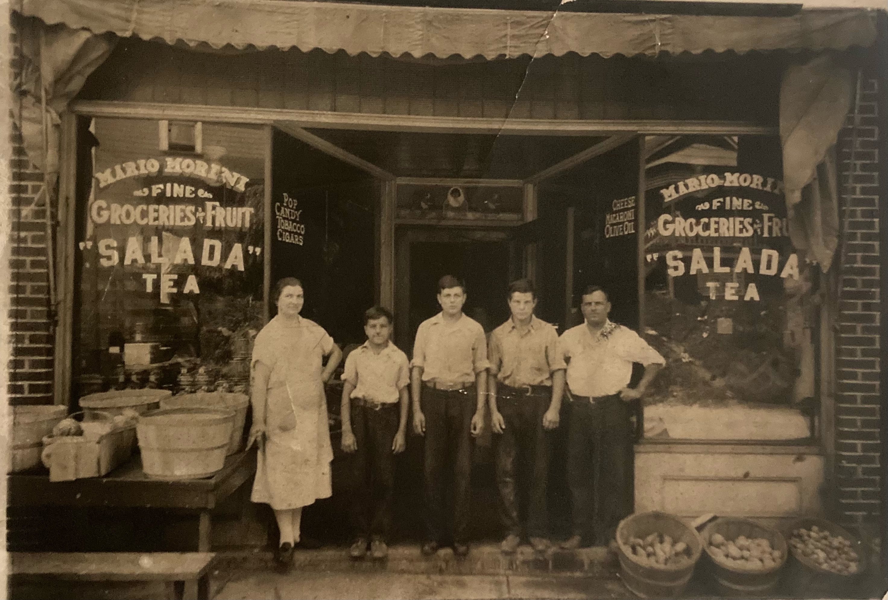 The Morini family standing in front of an old grocery store entrance